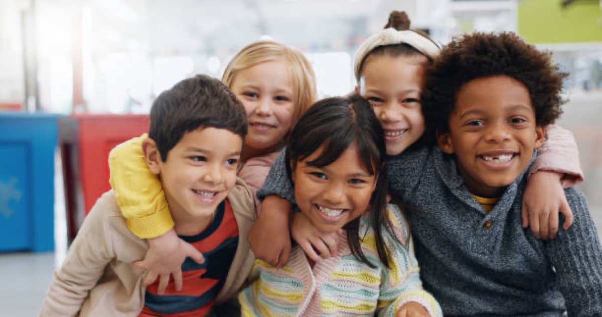 A diverse group of five smiling children together