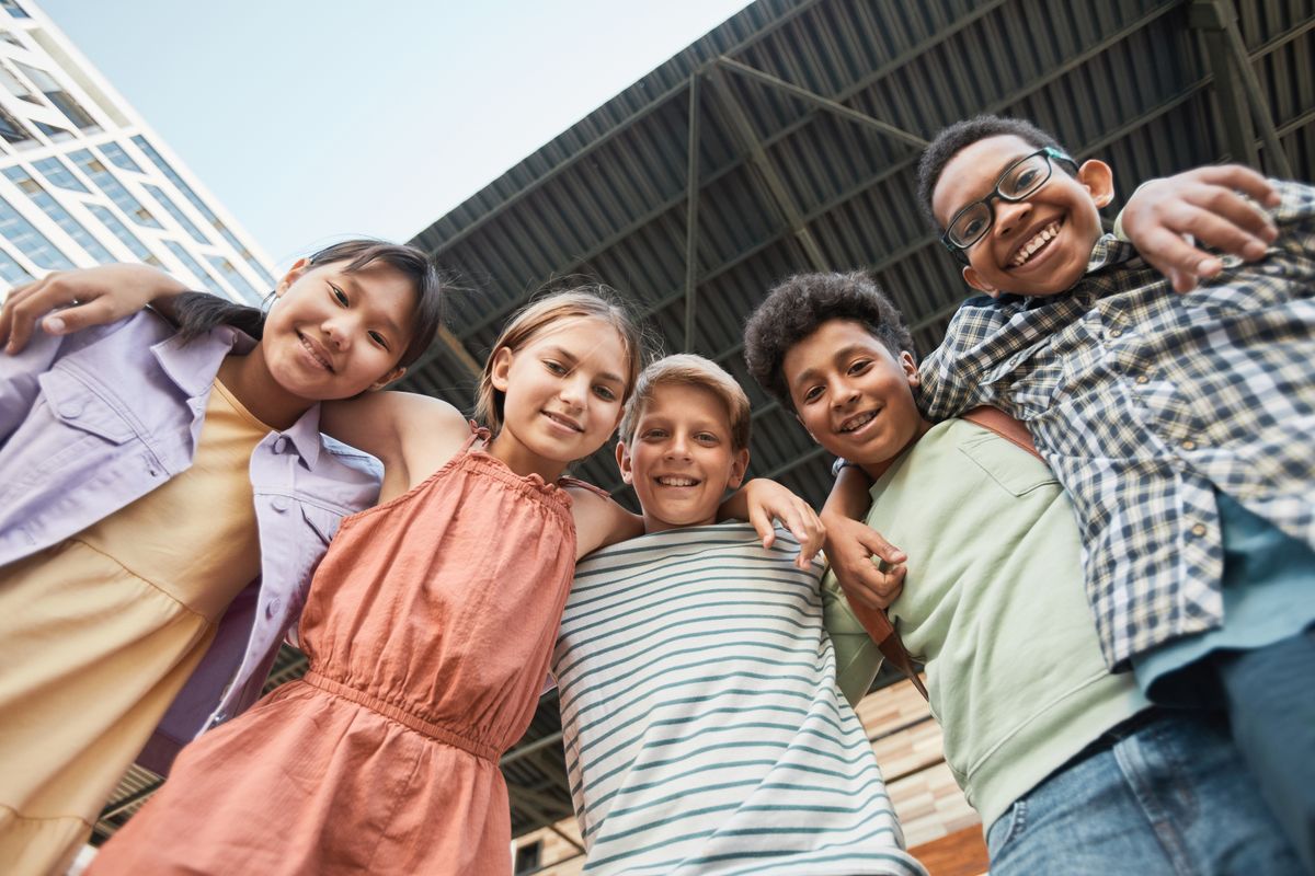 A diverse group of smiling children with arms around each other