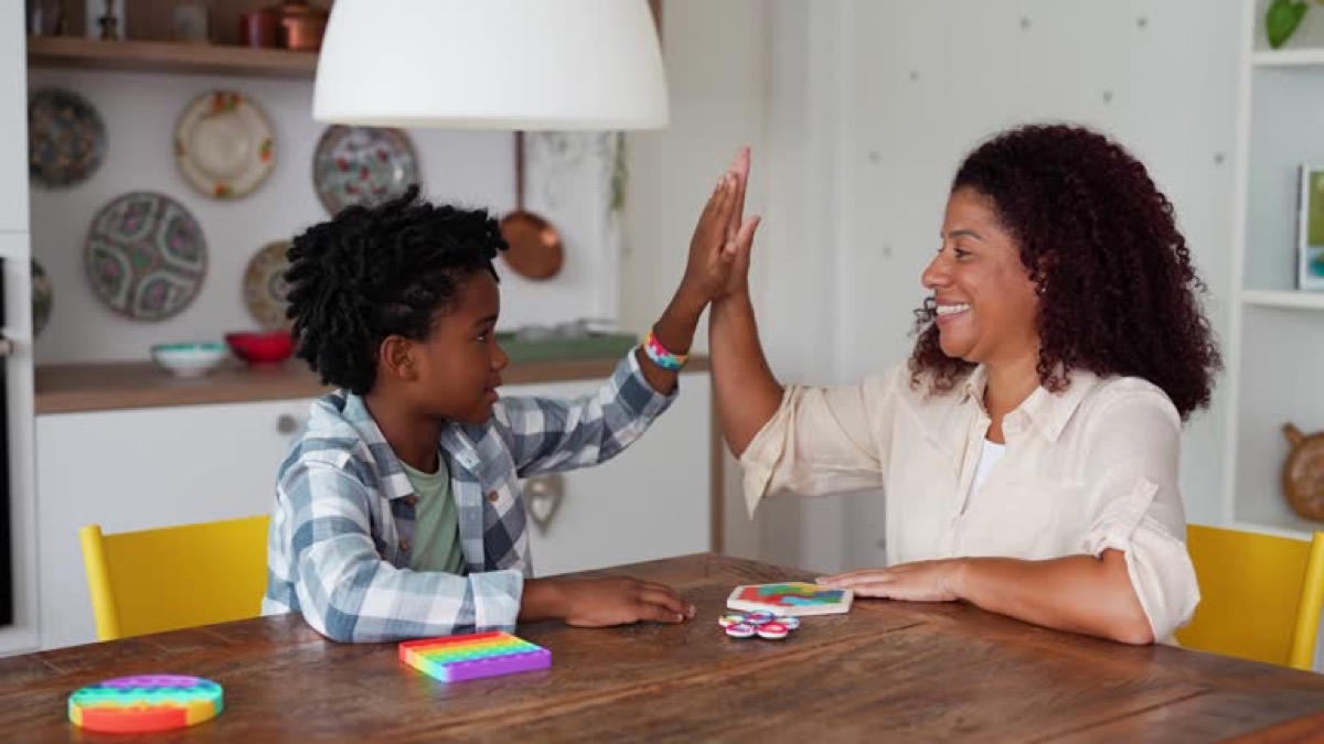 A parent and child sharing a high-five at a table