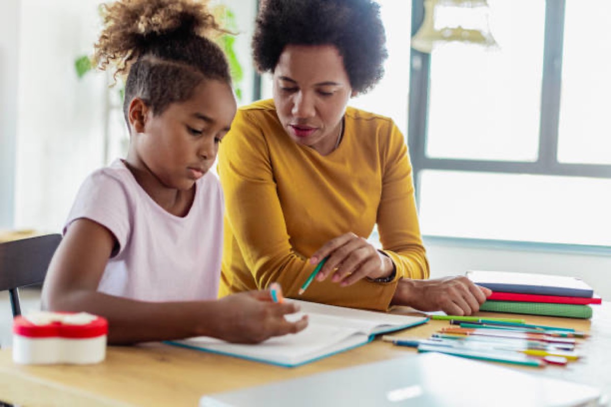 A parent helping a child with schoolwork at home