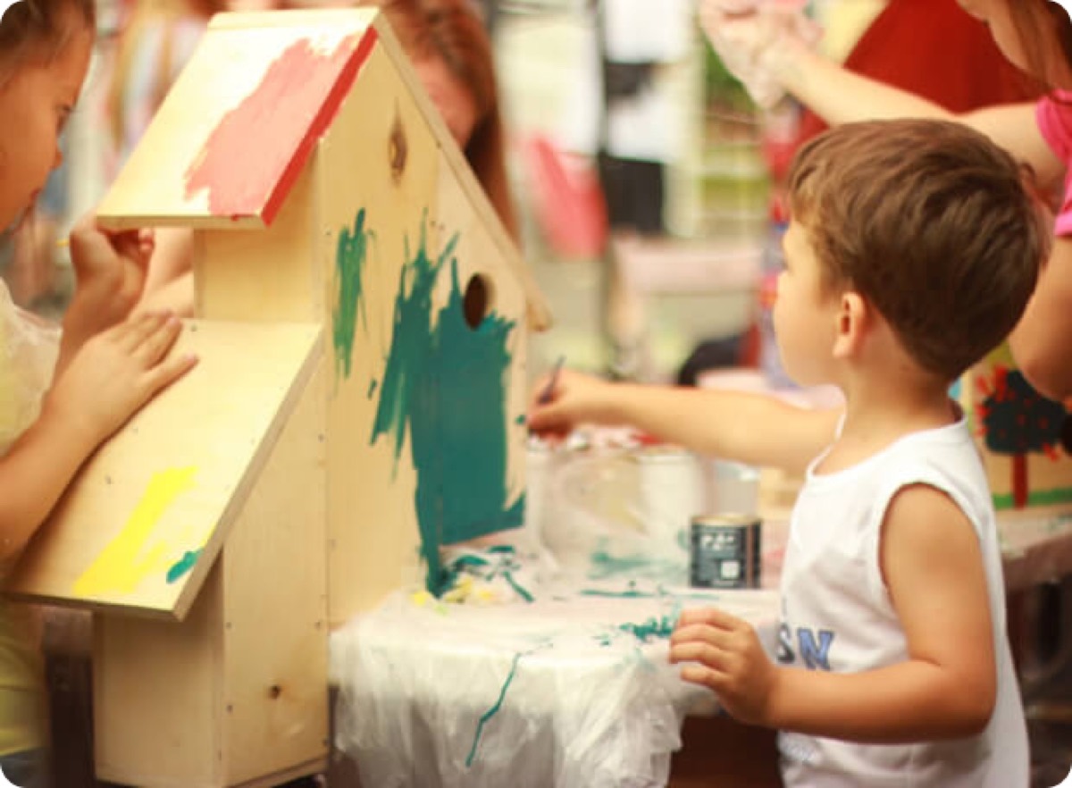 A child painting a wooden birdhouse